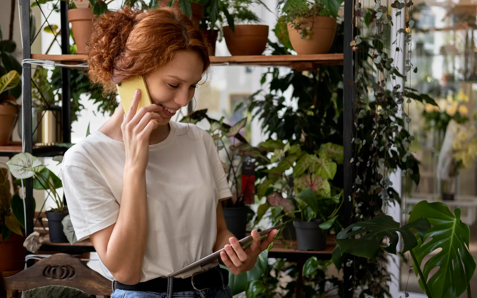 A shop owner checking something on a tablet while on the phone