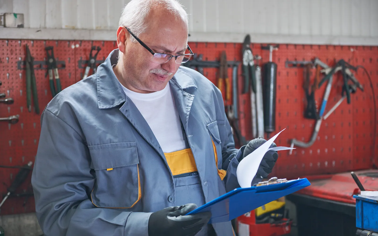 A mechanic reading a job sheet on a clipboard in his workshop